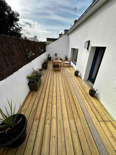 une terrasse en bois avec une table et des chaises sur une maison dans l'établissement Maison chez Emilie, à Trégunc