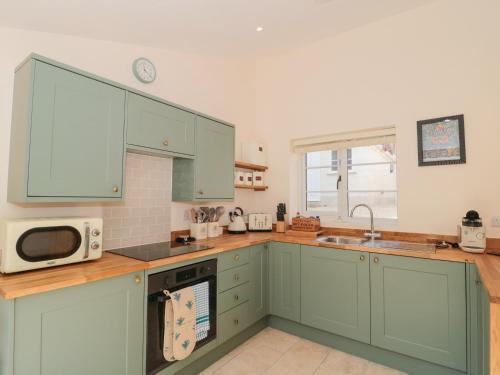 a kitchen with green cabinets and a microwave at The Nest in Bridgwater