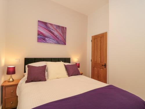 a bedroom with a large bed with purple pillows at The Nest in Bridgwater