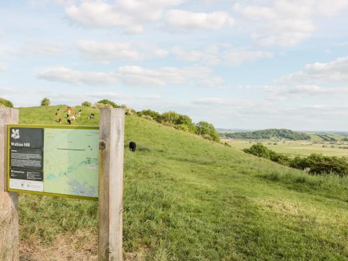 a sign on a hill with cows in a field at The Nest in Bridgwater