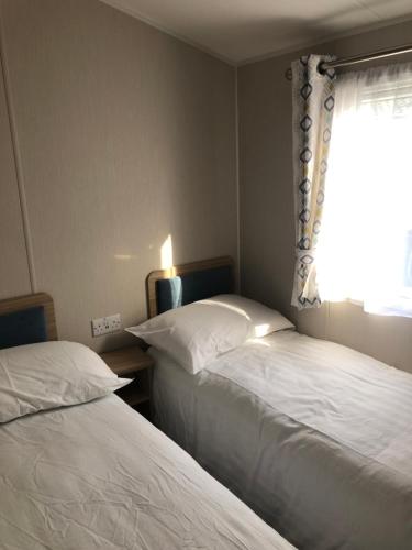 two beds in a small room with a window at Beach house fun in Walton-on-the-Naze