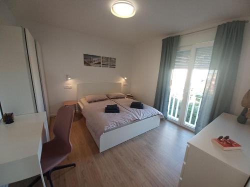 a bedroom with a bed and a desk and a window at Apartment Mare - lovely flat few steps away from the main bus station and Zadar old town in Zadar