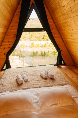 a bed with two slippers in a room with a window at Oda Riverside Cottages in Aragvispiri