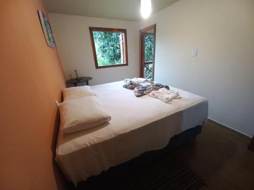 um quarto com uma cama grande com lençóis brancos e uma janela em Capim Rosa Chá em Mucugê