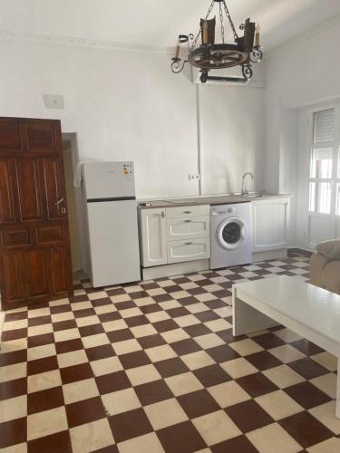 Kuchnia z podłogą wyłożoną szachownicą i białą lodówką w obiekcie Apartamentos Arquillo de Rota w mieście Sanlúcar de Barrameda