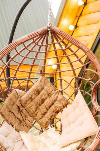 a rattan hanging chair with pillows on it at Oda Riverside Cottages in Aragvispiri