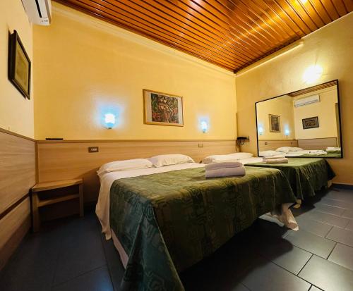 2 letti in una camera con un grande specchio di Hotel Nizza a Milano