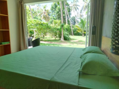 a bedroom with a bed and a large window at Green Villa Ahungalla in Balapitiya