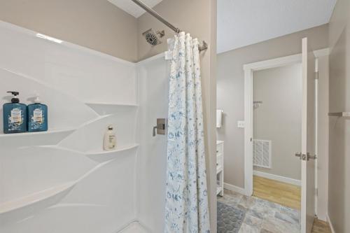 La salle de bains blanche est pourvue d'une douche avec rideau de douche. dans l'établissement Hot Tub -King Bed -3 Miles to Downtown -Simply, à Asheville