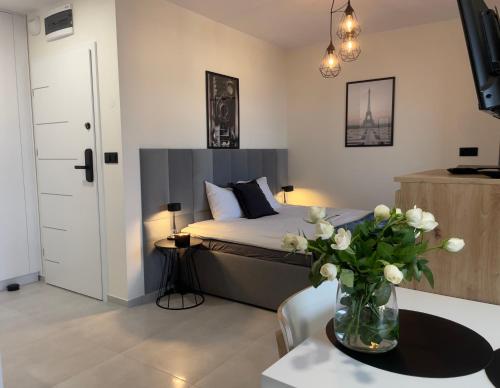 a bedroom with a bed and a vase of flowers on a table at URBAN APARTMENTS PREMIUM Baildona 18B, Free Garage, Self Check-in in Katowice