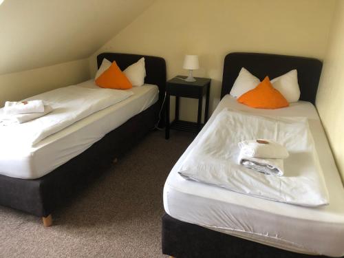 2 Betten in einem Zimmer mit orangefarbenen und weißen Kissen in der Unterkunft Hotel Gasthof am Waldeck in Oberthulba