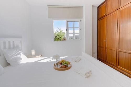 - une chambre blanche avec un lit et un bol de fruits dans l'établissement Amazing & Chill Terrace Palm Mar, à Palm-mar