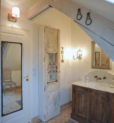 une salle de bain avec un lavabo et un miroir dans l'établissement L'Orangerie du Grand Jardin, à Condé-sur-Seulles