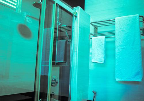 uma casa de banho com uma cabina de duche em vidro com paredes azuis em Maaniya Palace em Maamigili