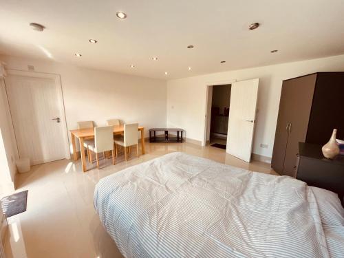 a bedroom with a bed and a table and chairs at Large studio flat B near Heathrow in New Bedfont