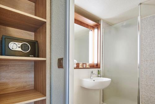 a bathroom with a shower and a sink and a mirror at The Originals City Hôtel La Verrière-Yvelines in La Verrière