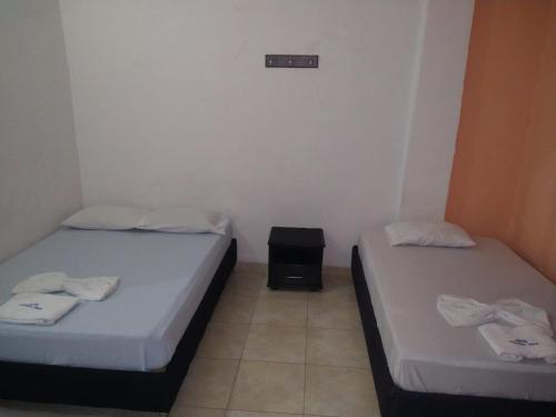 two twin beds in a room with a small table at Hotel Central Park in El Espinal