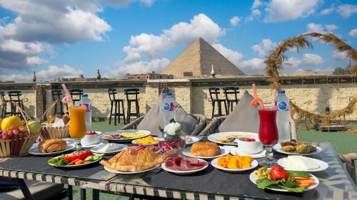 a table full of food with the pyramids in the background at King Cheops Inn - Pyramid View in Cairo