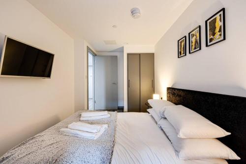 - une chambre avec un lit doté d'oreillers blancs et une télévision dans l'établissement Modern & Centrally Located Apartment, à Liverpool