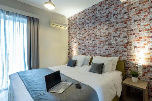 a bedroom with a brick wall and a bed with a laptop at Nantin Hotel Ioannina in Ioannina