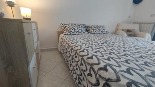 una camera da letto con un letto con un piumone bianco e nero di Rosi Room a Giucano