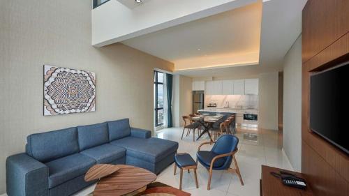 a living room with a blue couch and a kitchen at Tribeca Serviced Hotel by Millennium in Kuala Lumpur