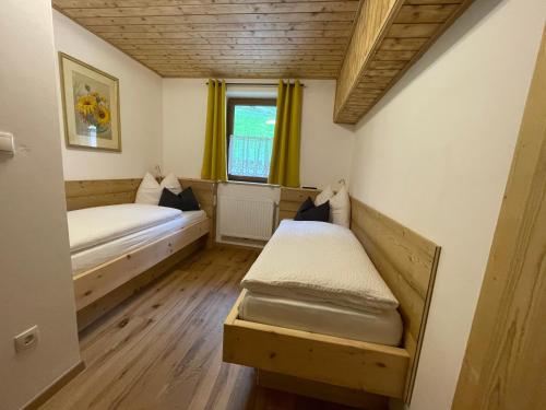 a small room with two beds and a window at Stroblhof in Vipiteno