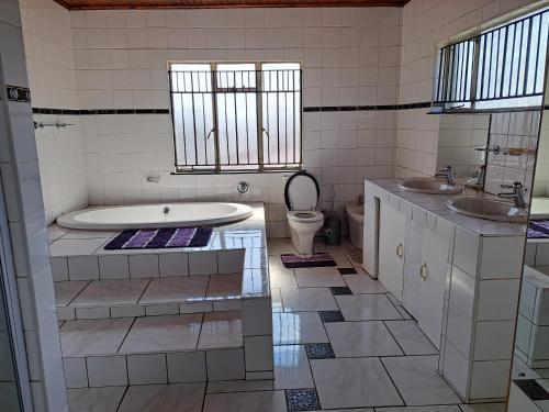 a bathroom with a tub and two sinks and a toilet at Gae la boroko @legodi's in Brakpan