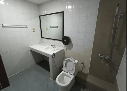 OYO 90809 Oriental Hotel في Sarikei: حمام مع مرحاض ومغسلة ومرآة