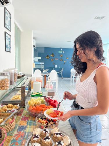 uma mulher está a preparar comida num buffet em Hotel Pousada Da Sereia em Maceió