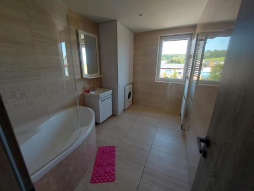 ein Bad mit einer Badewanne und einem Fenster in der Unterkunft Apartmán Rudoltice 