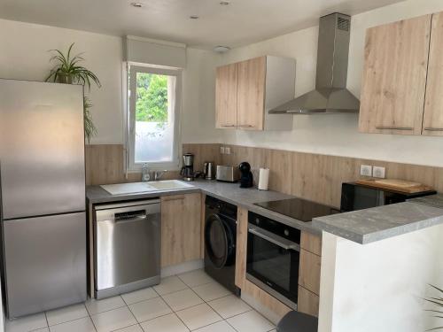 La cuisine est équipée d'un lave-vaisselle, d'un évier et d'un réfrigérateur. dans l'établissement Jolie maison avec jardin, à Honfleur