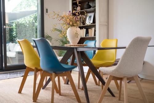 une table à manger avec des chaises jaunes et bleues dans l'établissement LUJOSO CHALET CON PISCINA PRIVADA, JARDIN Y DOMÓTICA EN PUERTA DE HIERRO, à Madrid