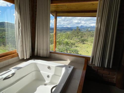 eine Badewanne in einem Zimmer mit einem großen Fenster in der Unterkunft Chalé Terrarum in Santo Antônio do Pinhal
