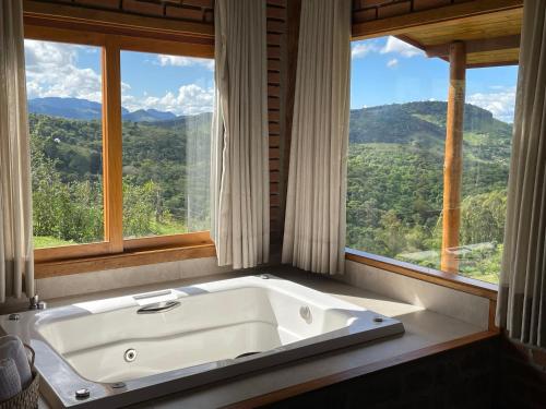 een bad in een kamer met een groot raam bij Chalé Terrarum in Santo Antônio do Pinhal