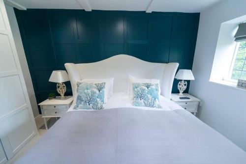 a bedroom with a large white bed with blue walls at Weaver's Cottage in Smarden