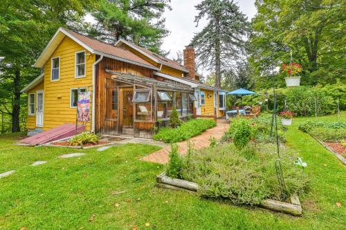 a yellow house with a garden in the yard at Canandaigua Getaway with Deck and Sunroom! in Canandaigua
