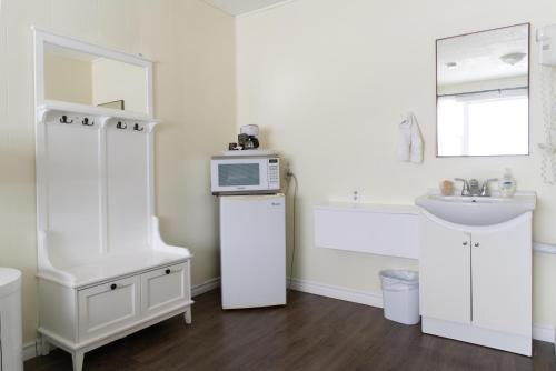 a white bathroom with a sink and a microwave at Lakeside Inn in Orillia