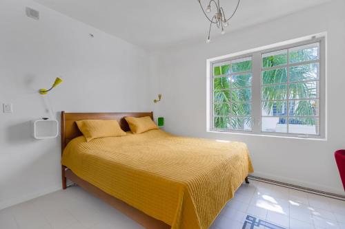 ein Schlafzimmer mit einem Bett mit gelber Tagesdecke und einem Fenster in der Unterkunft Palm-Fringed Paradise in South Beach in Miami Beach