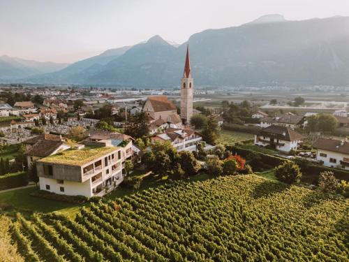 - une vue aérienne sur un petit village avec une église et des vignobles dans l'établissement Boutique-Hotel Ballguthof am Golfplatz, à Lana