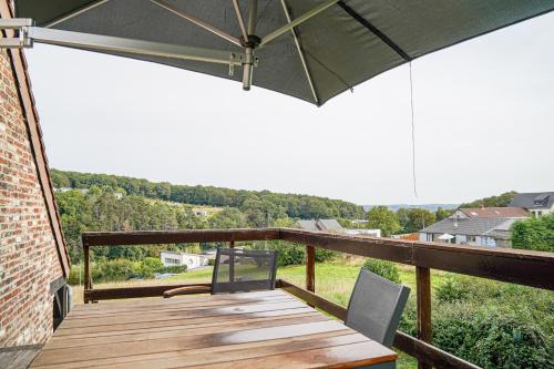 una terrazza in legno con tavolo e ombrellone di Gite L'Ecureuil - Appartement 4 personnes à Wépion (Namur) a Namur