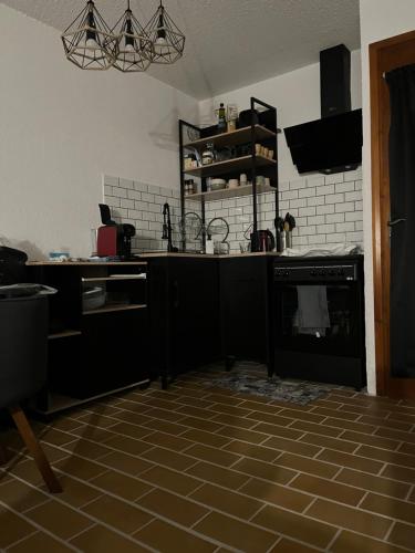 een keuken met zwarte kasten en een tegelvloer bij Lilaubaoli in Valdeblore
