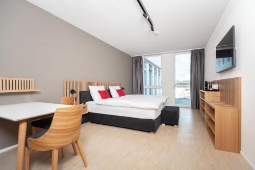 1 dormitorio con 1 cama, escritorio y TV en Tailormade Hotel BAB Bachenbülach, en Bachenbülach