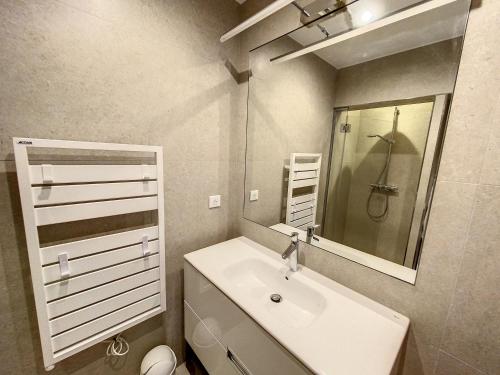 une salle de bain blanche avec un lavabo et un miroir dans l'établissement Mazet*** vue mer, centre et plage à pied, à Sainte-Maxime