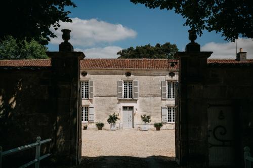 une ancienne maison en pierre avec un portail en face de celle-ci dans l'établissement Beautiful riverside boathouse, à Bourg-Charente