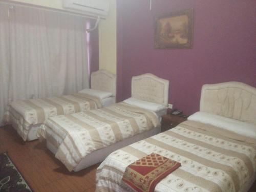 three beds in a room with purple walls at Hotel Room with Breakfast -Beni sweif in Beni Suef