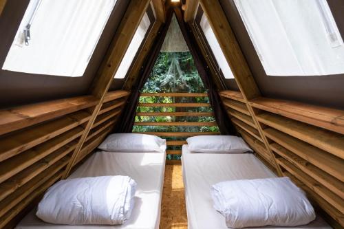 Casa Dei Prati Camping Village في لاكونا: سريرين في غرفة بها نافذتين