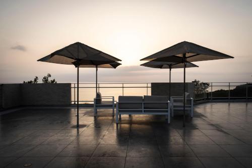 two benches and two umbrellas on a roof at Côté Thalasso Hôtel & Spa Marin in Banyuls-sur-Mer