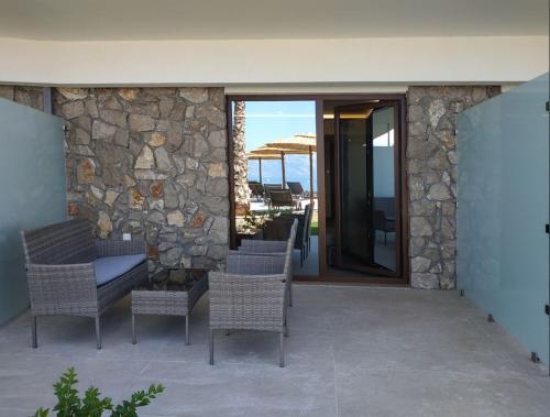 a patio with chairs and a stone wall at Anthidon Nature Estate & Farm in Chalkida