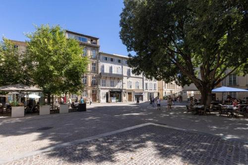 a city street with tables and trees and a building at Le balcon du roi René in Avignon